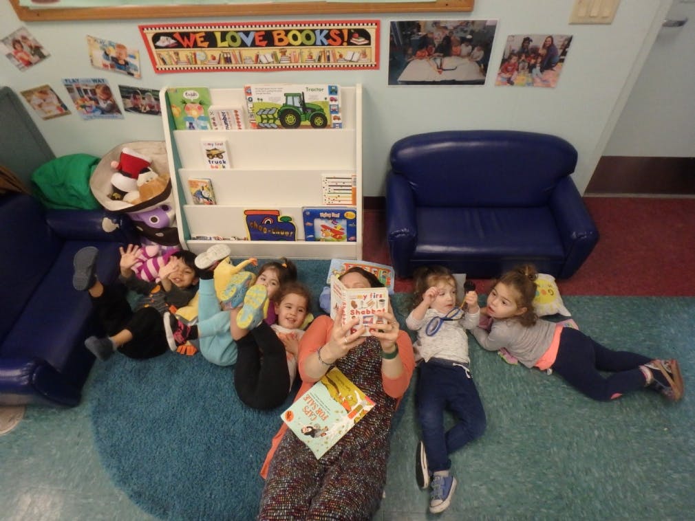 Adult reading to children lying on the floor in a classroom