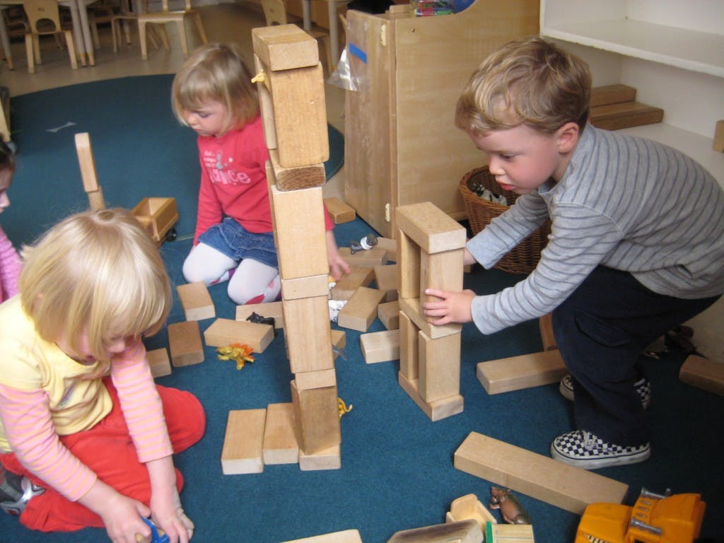 Children playing with wooden blocks in a classroom
