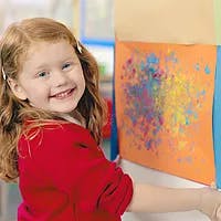 Child smiling next to a colorful painting