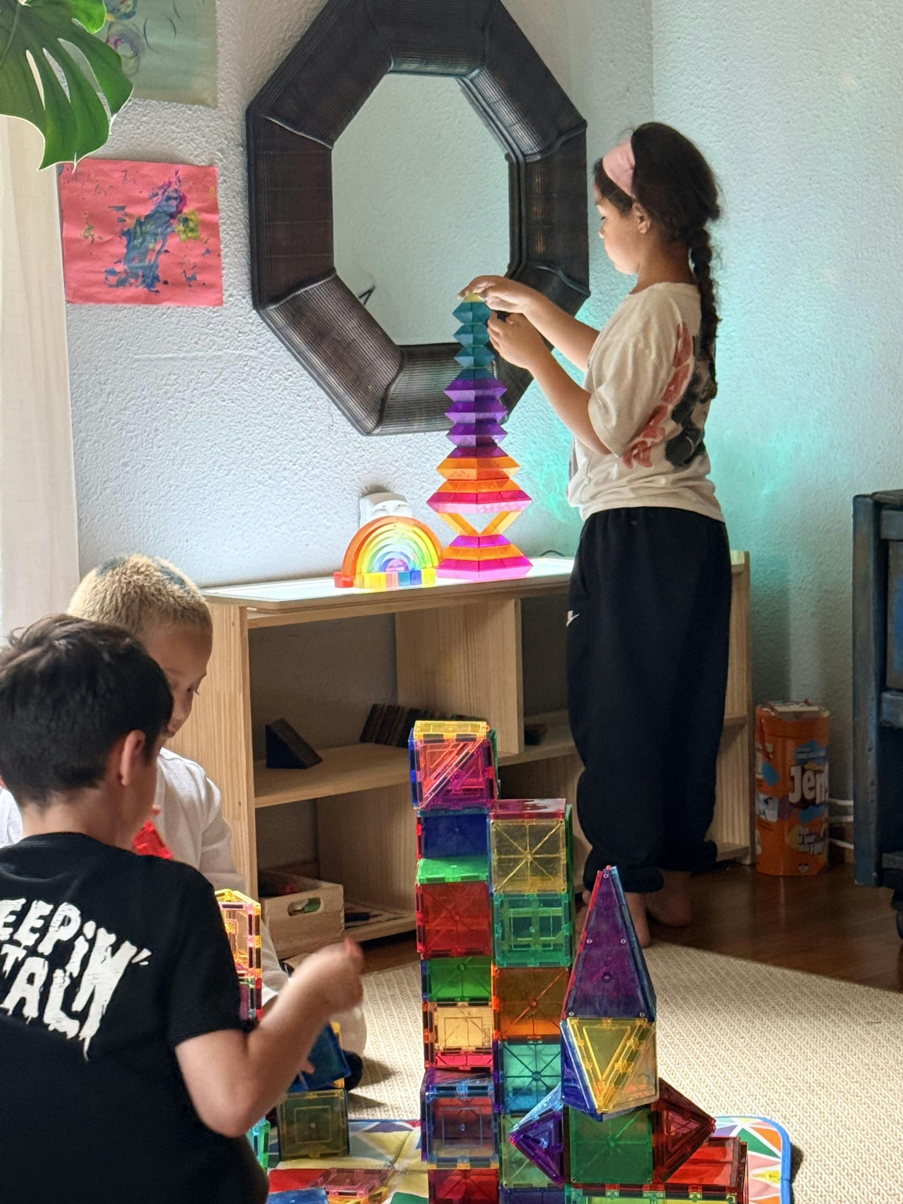 Three children playing with colorful magnetic building tiles