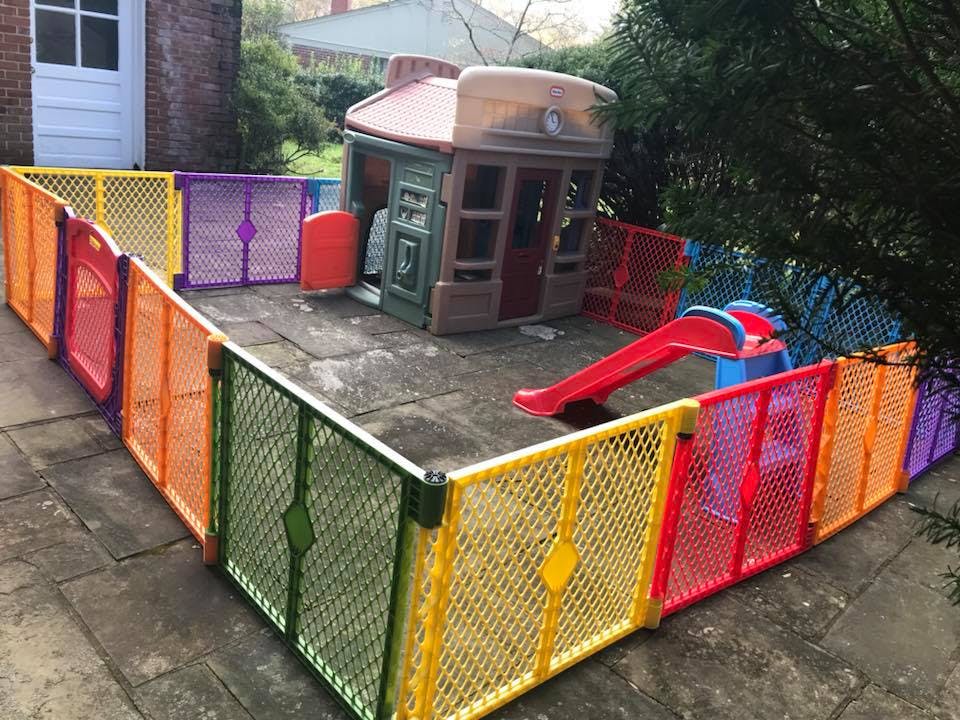 Colorful playpen enclosing a playhouse and slide on a patio