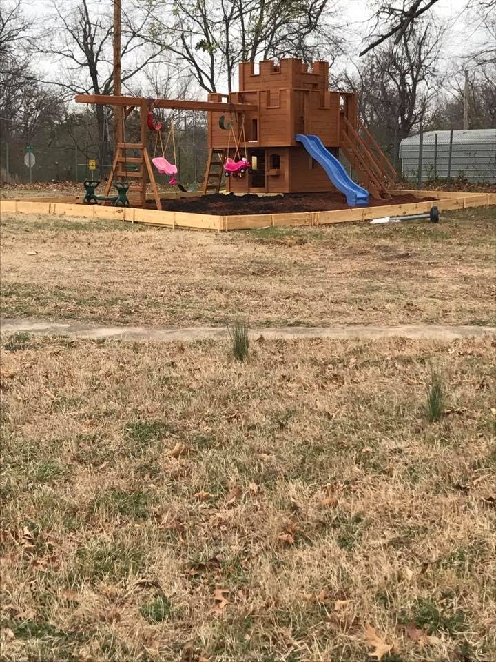 Wooden playground set with swings and a blue slide