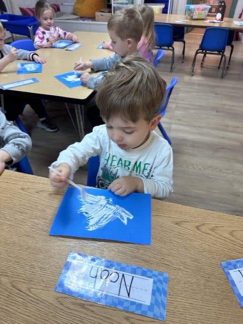 Children painting at a table in a classroom