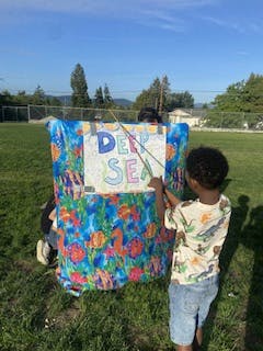 Child playing with a Deep Sea themed puppet stand outdoors