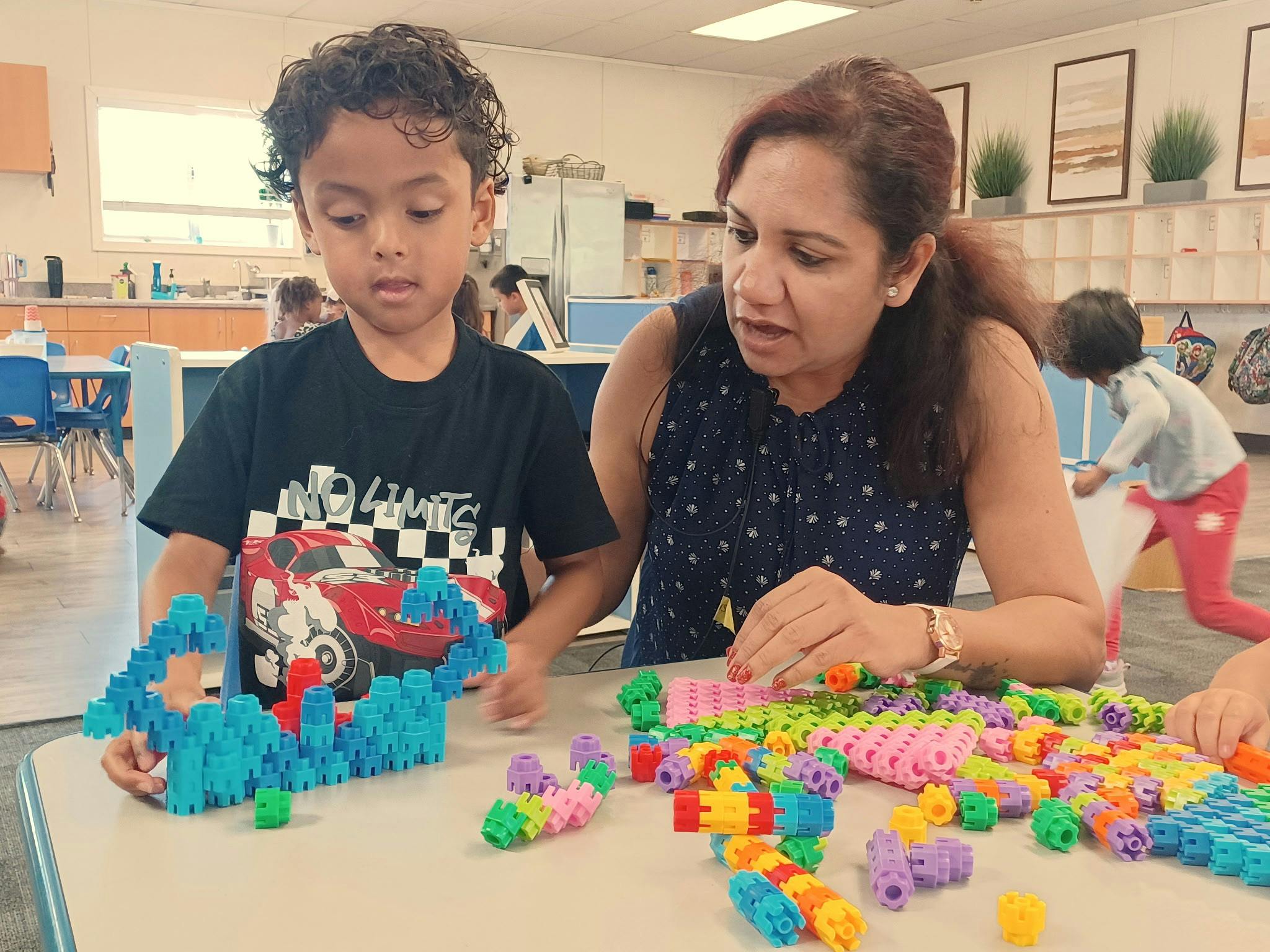 Child and adult playing with plastic interlocking building blocks in a classroom