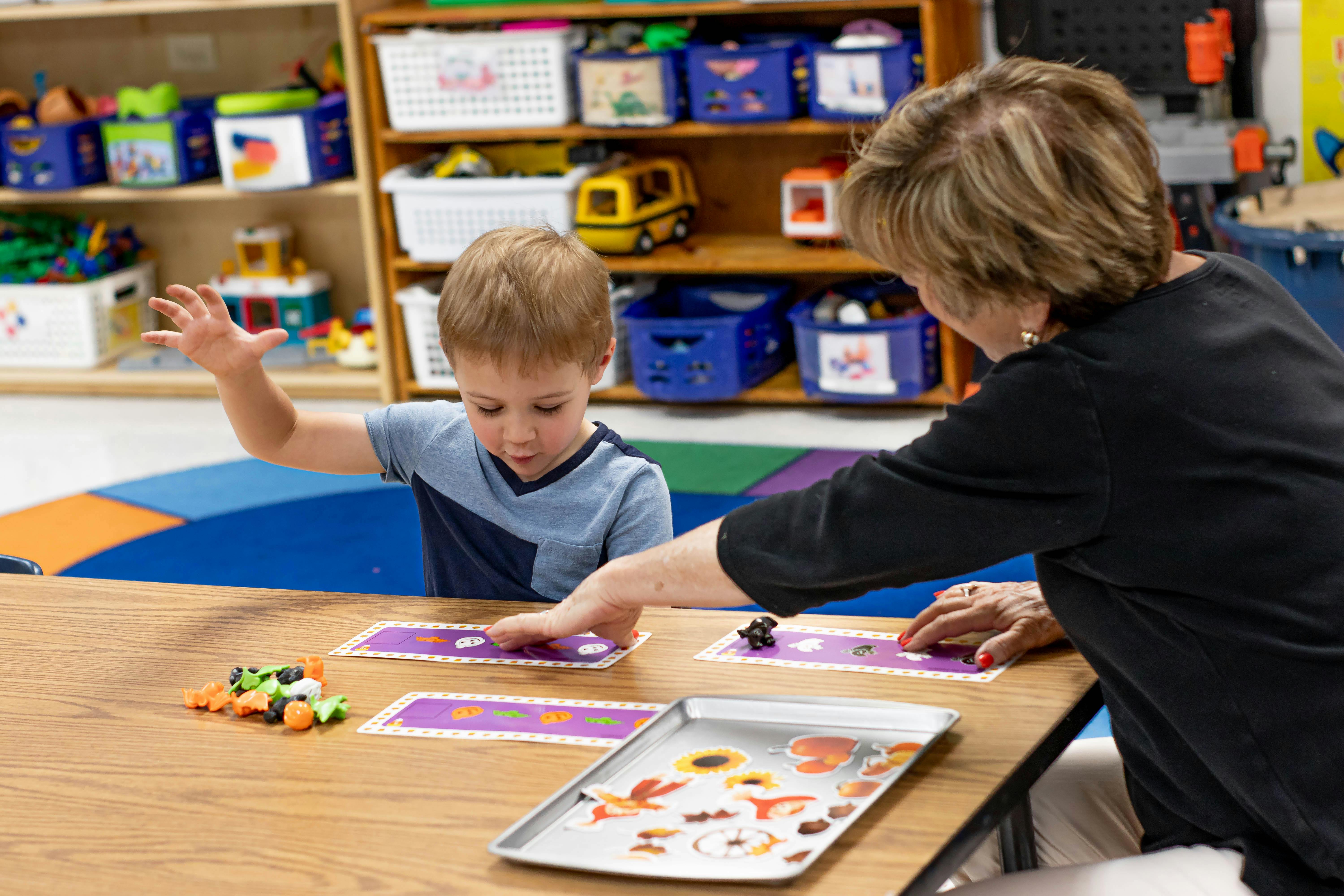 Adult and child playing with cards and small objects at a table