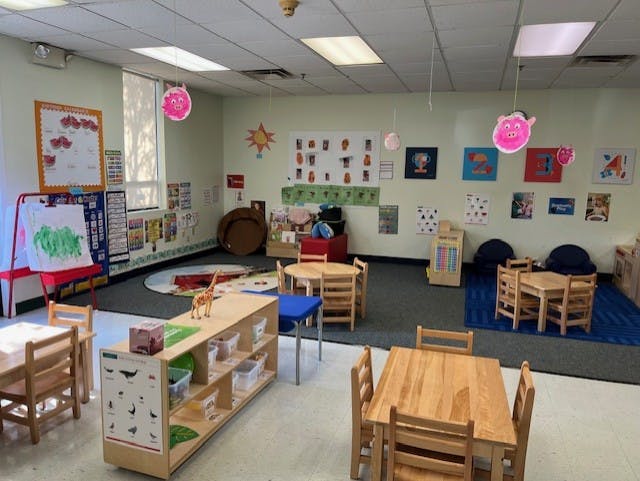 Empty colorful preschool classroom with small tables, chairs, and learning materials
