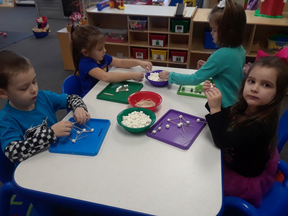 Children making shapes with toothpicks and marshmallows in a classroom