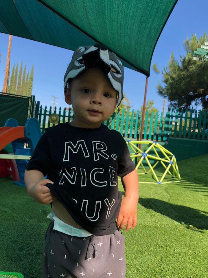 Child wearing a hat and a shirt that says "MR. NICE GUY"