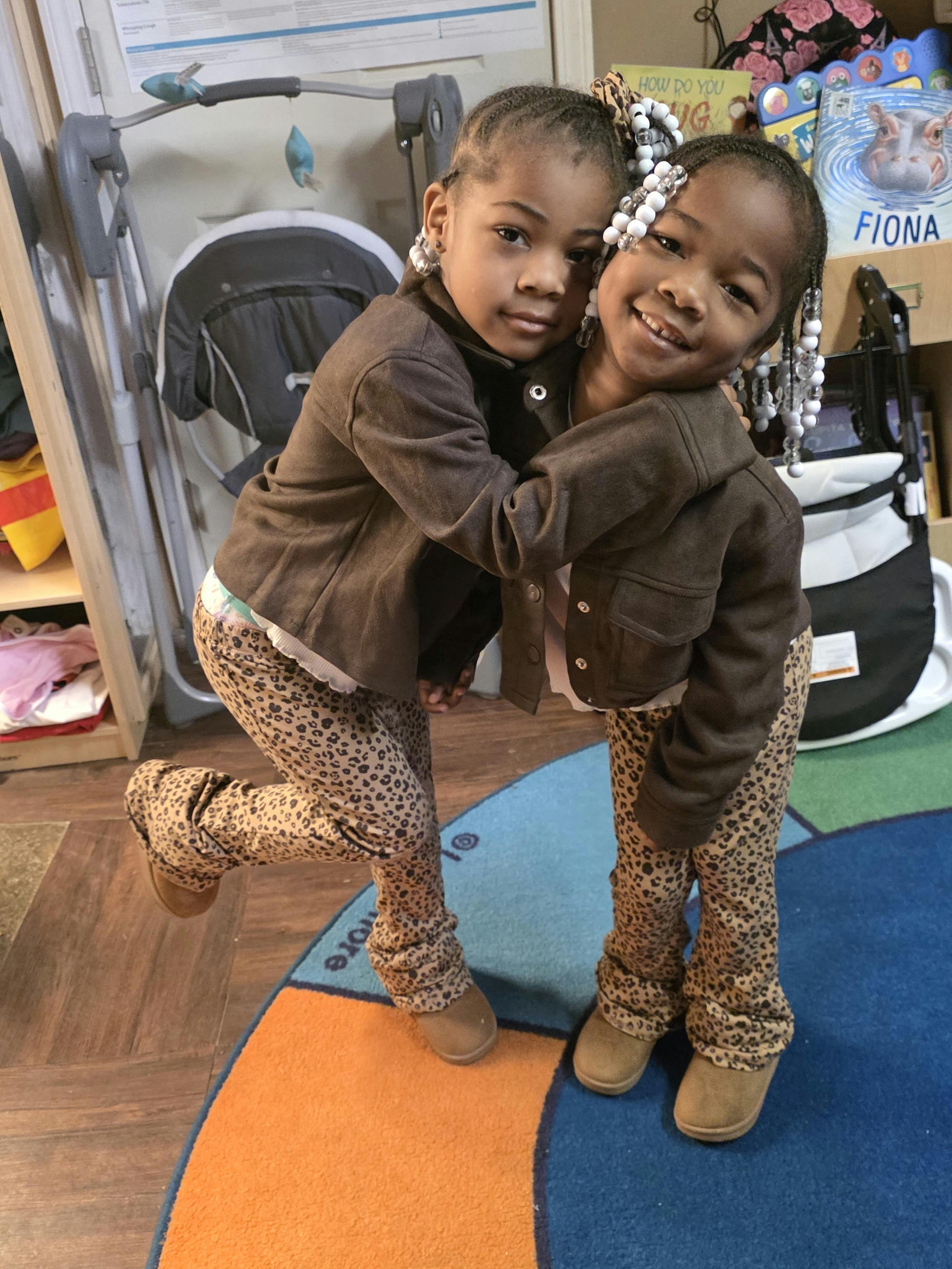 Two children embracing, one smiling and one looking at the camera