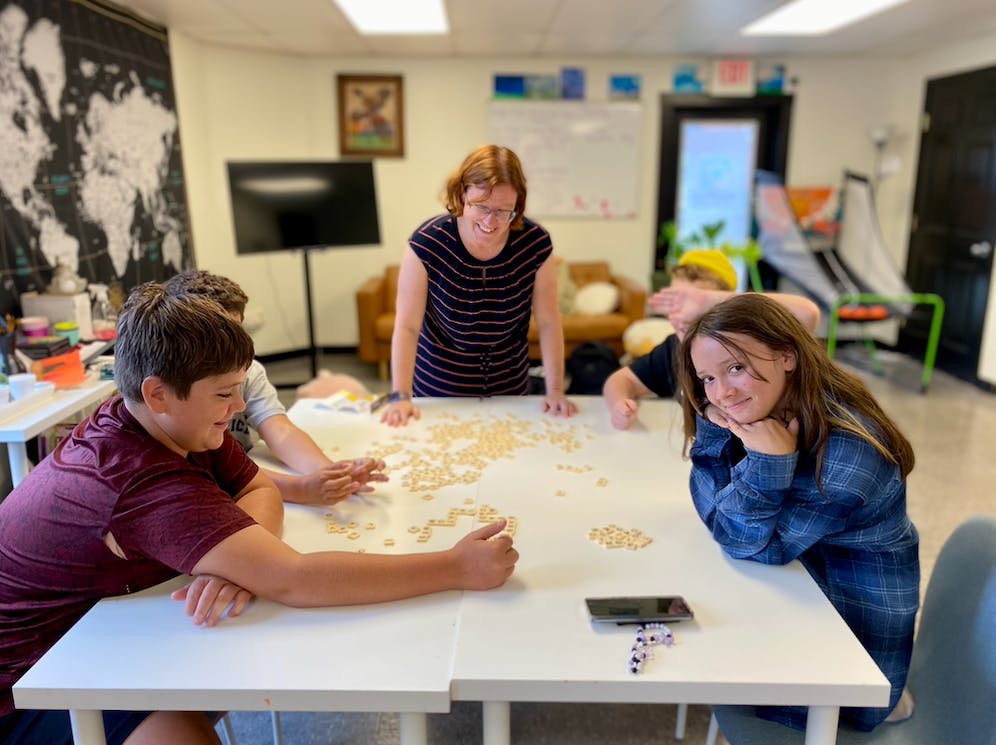 Adult and teens playing a game with small wooden blocks on a table