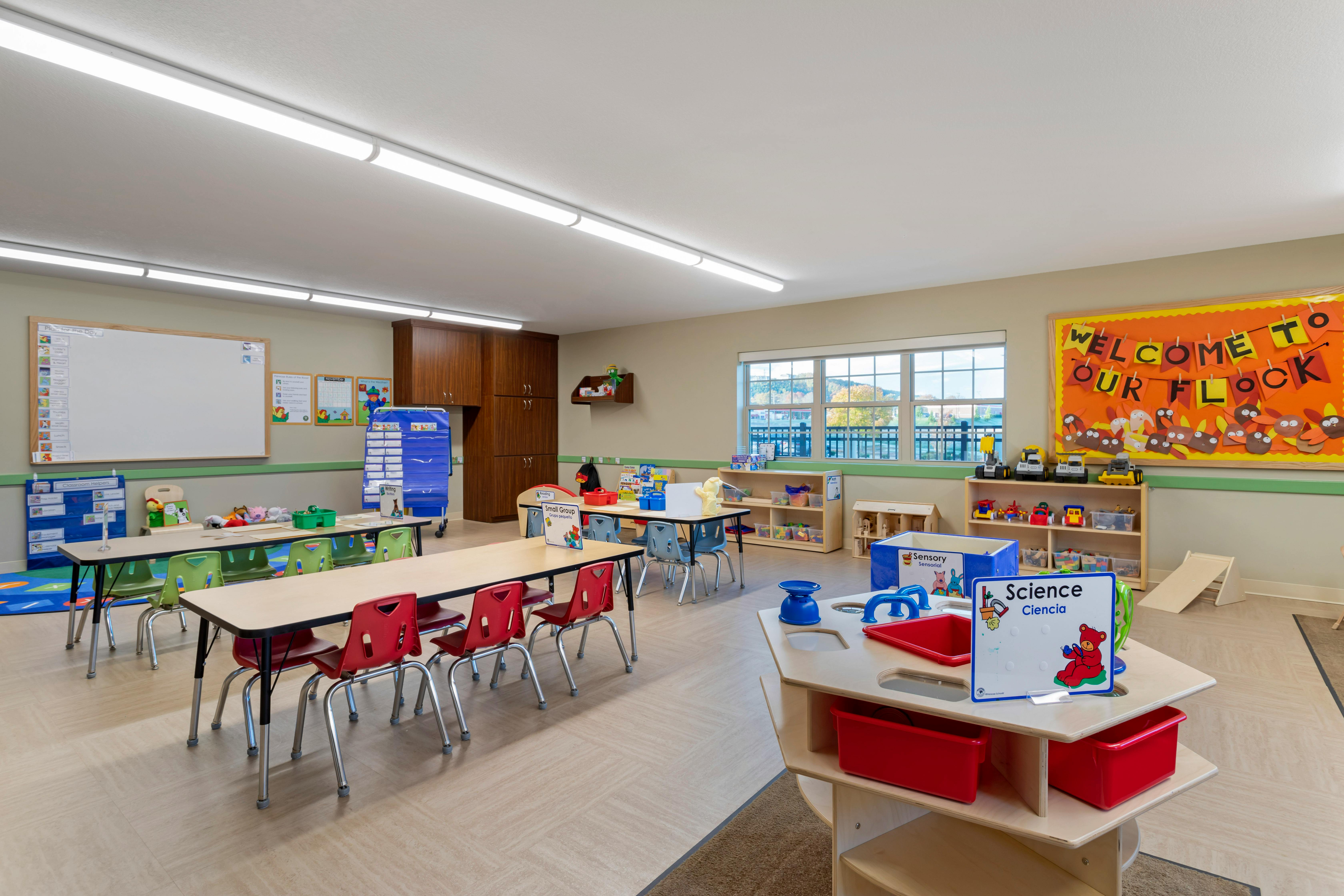 Classroom with child-sized tables and chairs, toys, and educational posters