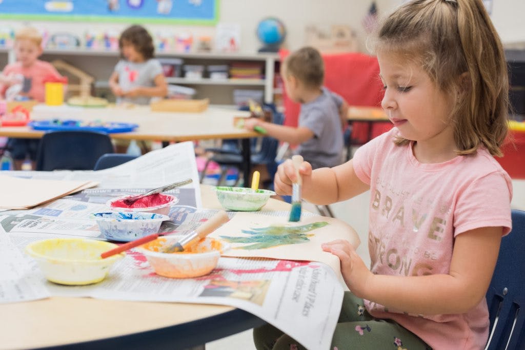 Child painting at a table in a classroom