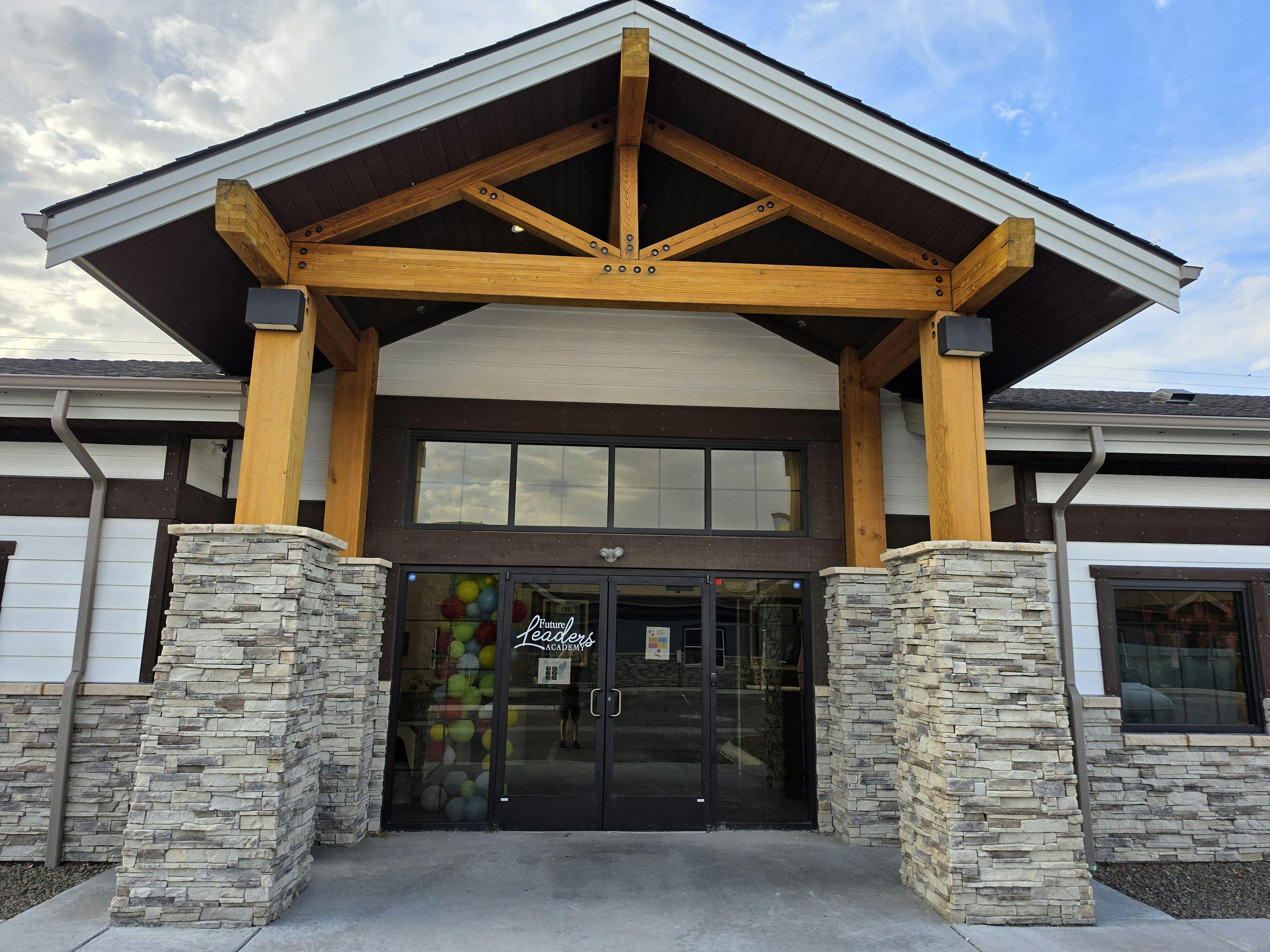 Building entrance with a prominent wooden beam roof structure over glass doors