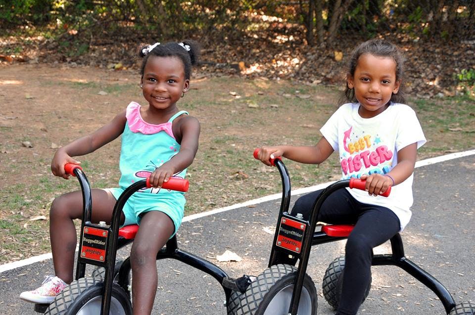 Two children sitting on tricycles outdoors