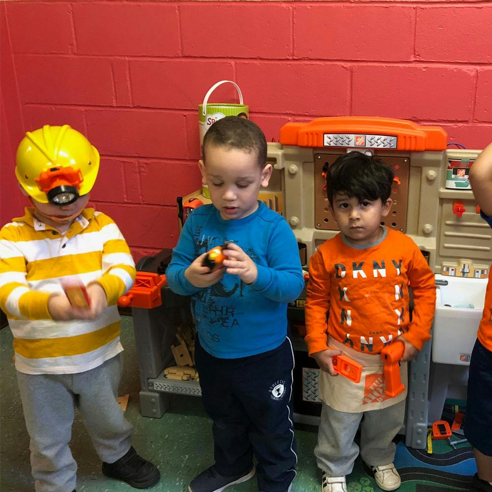 Three children playing with toys in a classroom