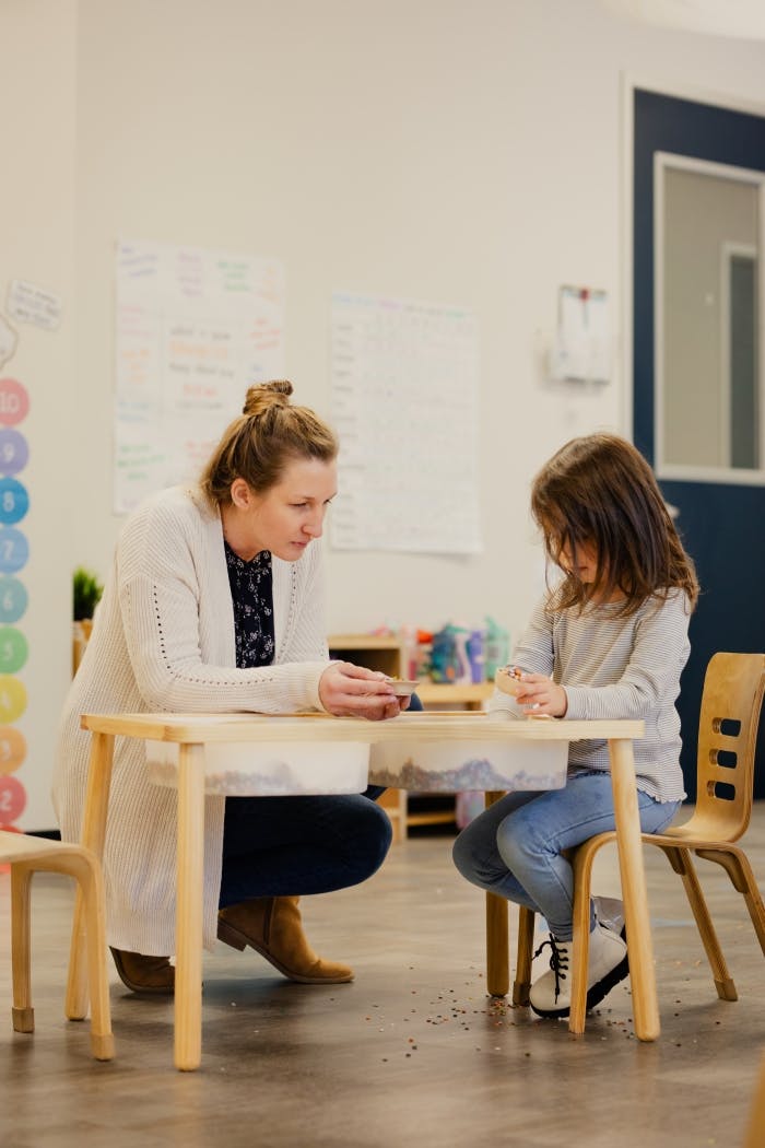 Adult and child at a small table in a classroom