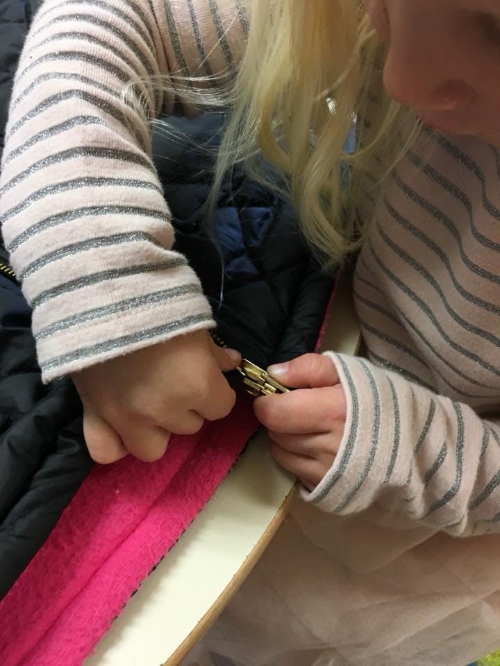 Child's hands zipping up a jacket