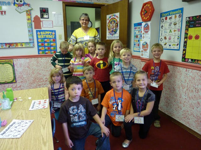 Adult and multiple children posing in a classroom