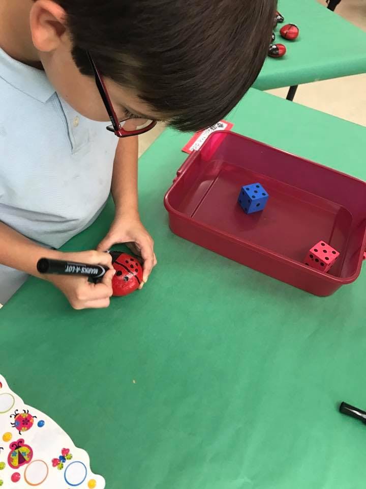 Child drawing on a ladybug-shaped object with a marker