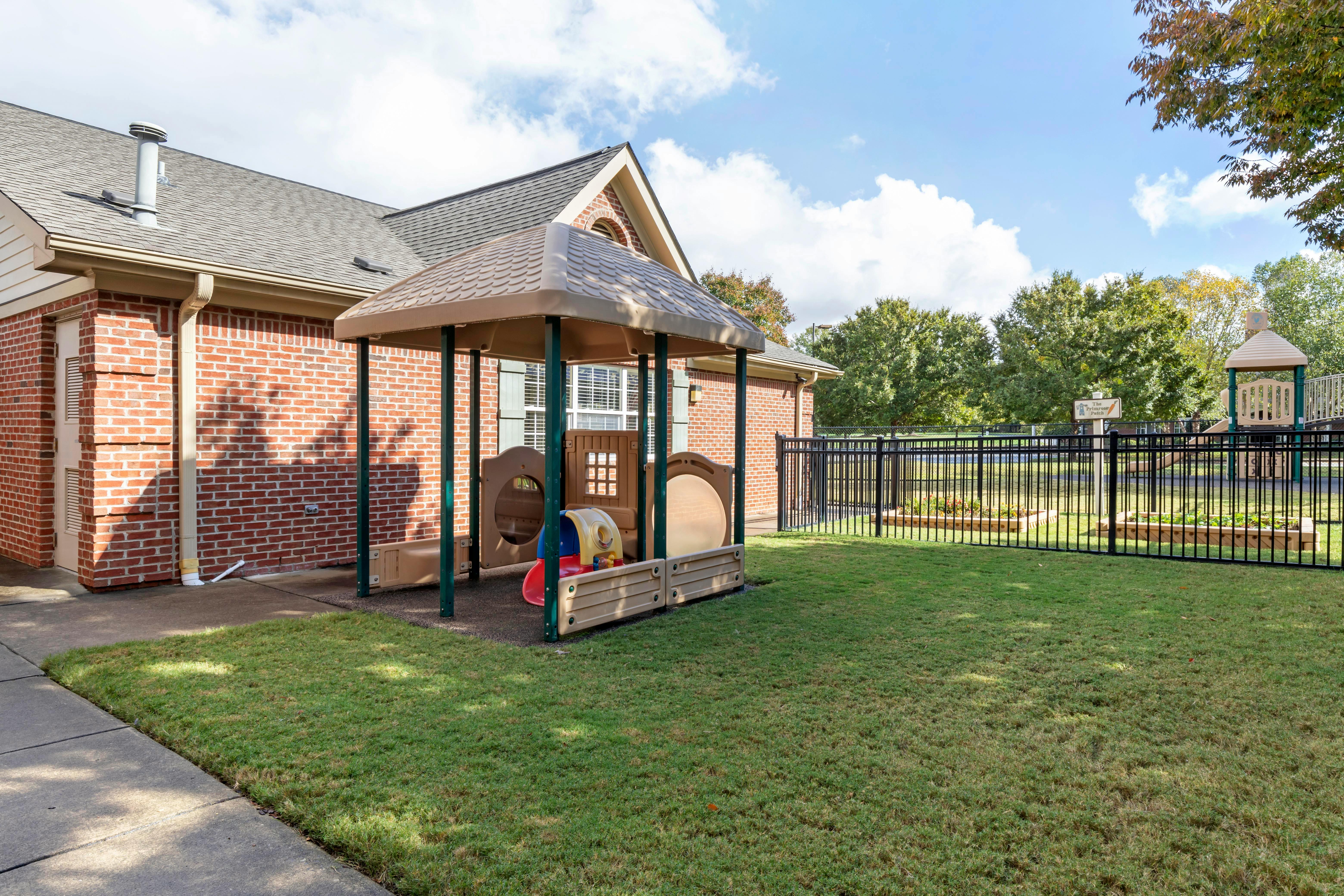 Childcare outdoor play area with playground equipment and a brick building