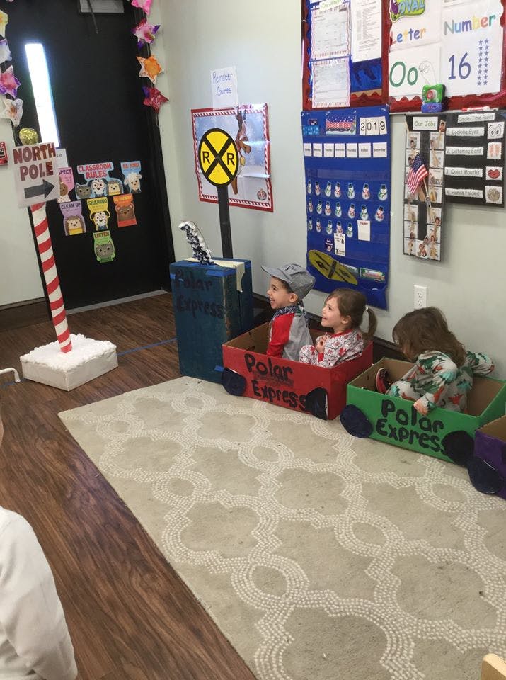 Children sitting in cardboard boxes labeled "Polar Express" in a classroom