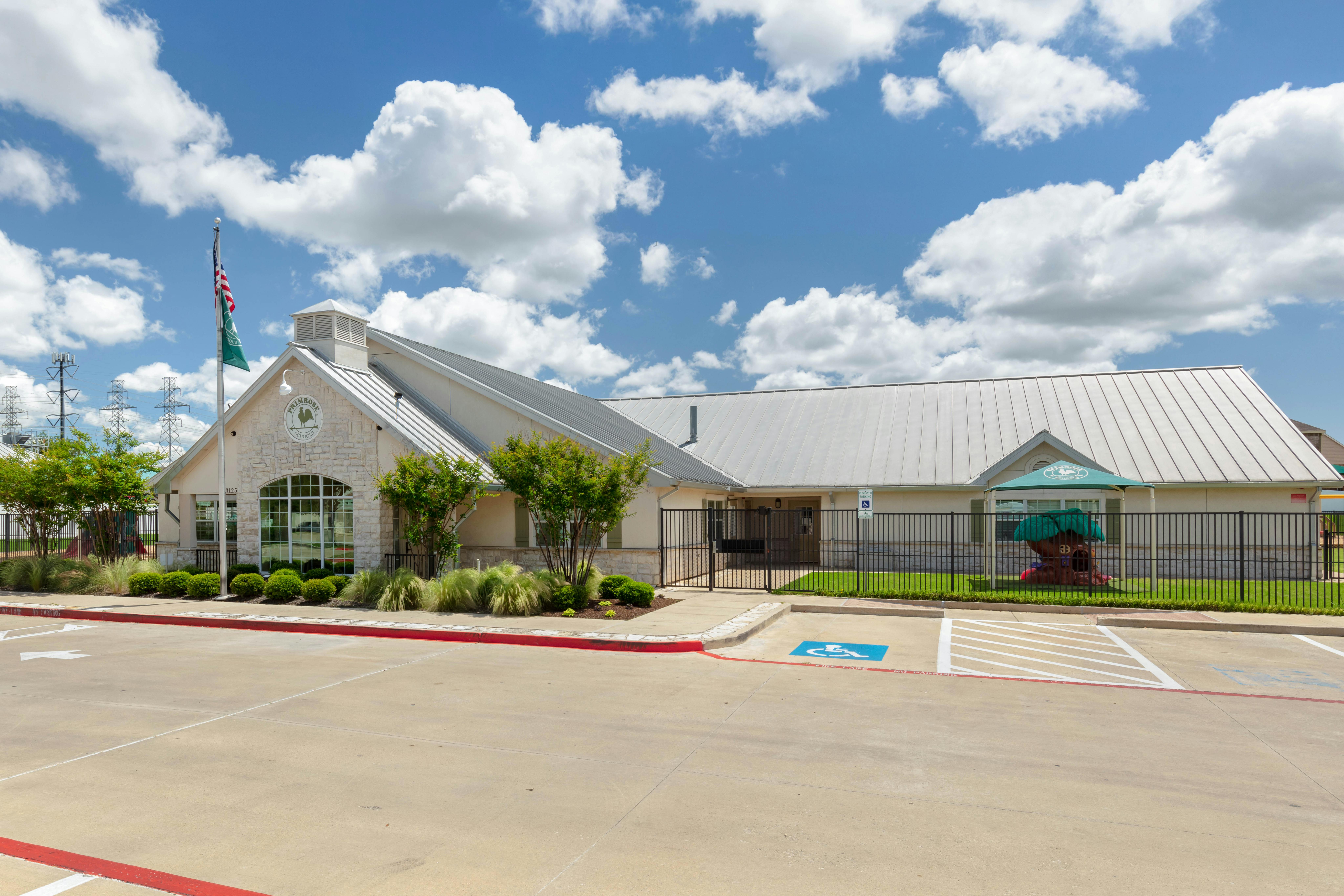 An outdoor view of a school building with a metal roof and a flagpole