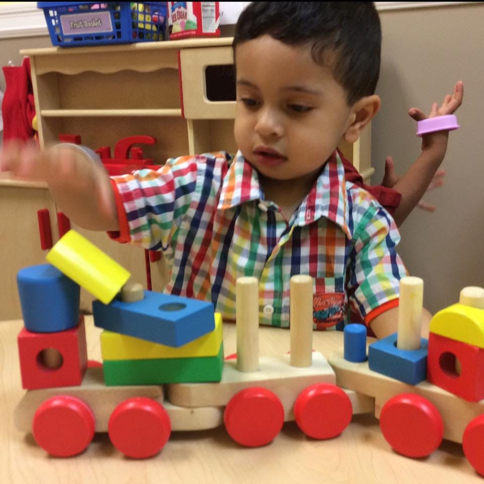 Child playing with a wooden toy train with colorful blocks