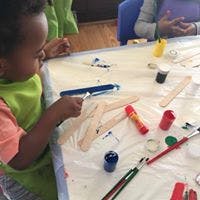 Child painting on a table with craft supplies