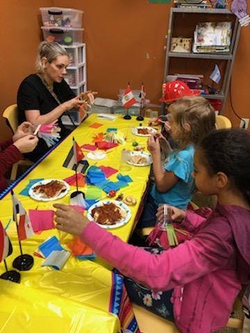 Adult and children at a table with food and small flags