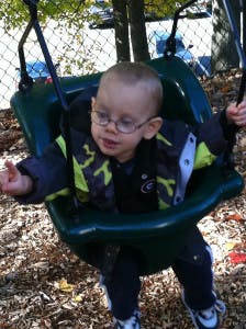 Child in glasses sitting in a swing