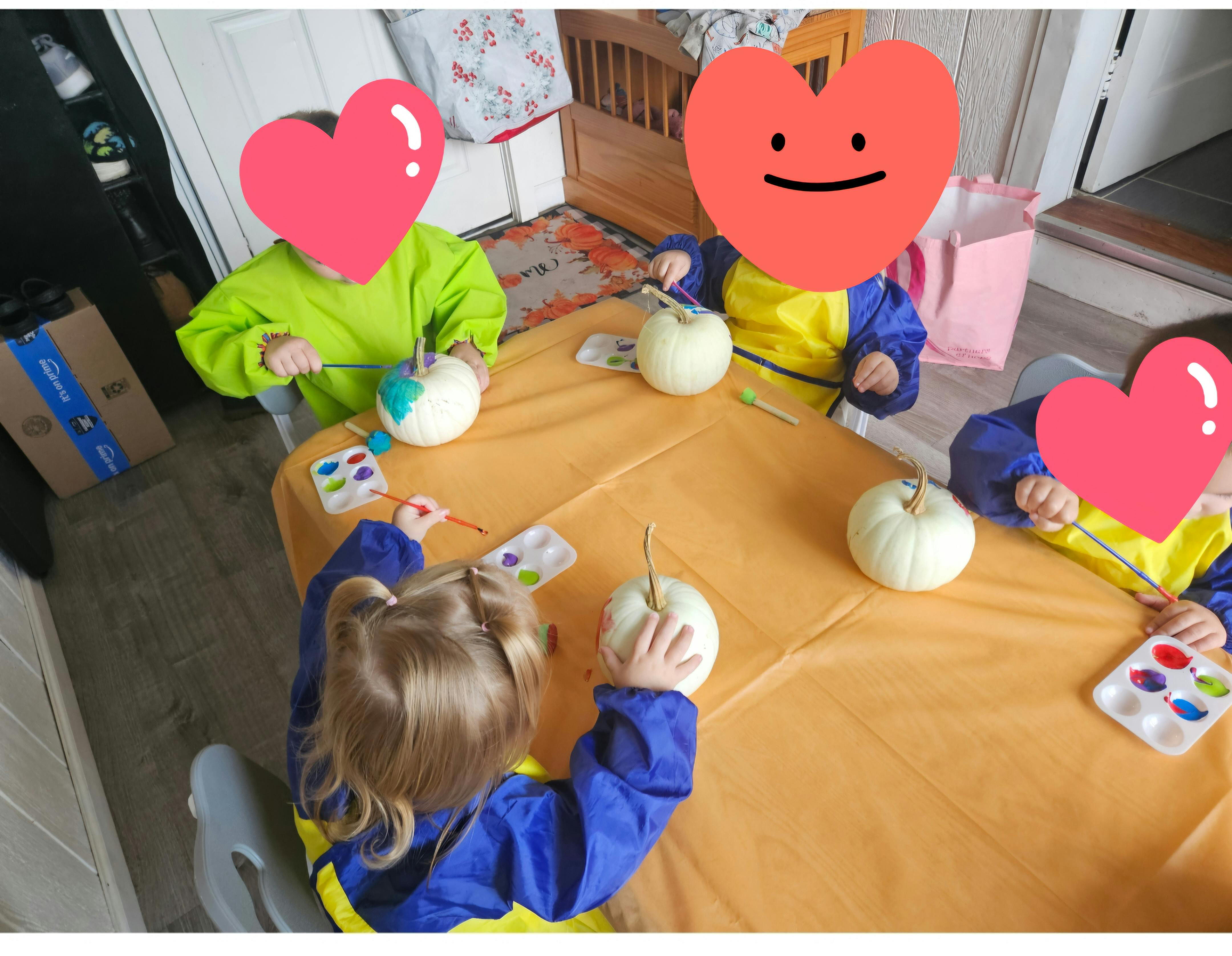 Children painting pumpkins around a table