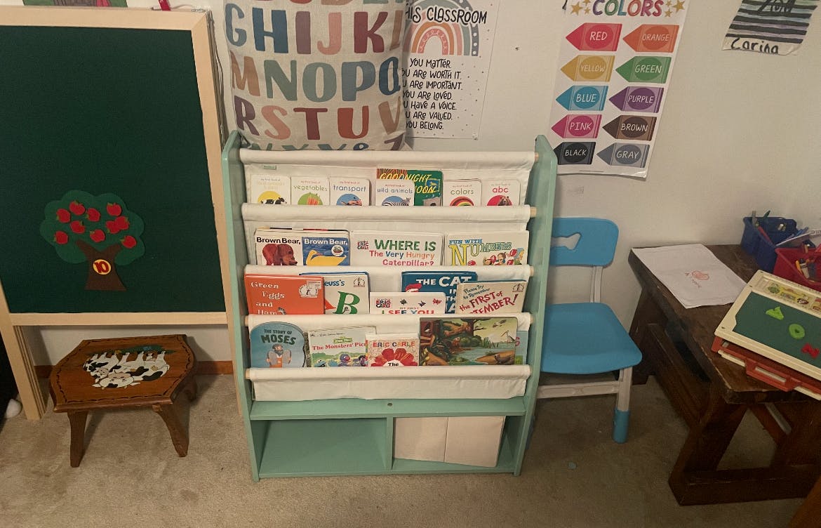 Bookshelf with children's books, a chalkboard, and a small blue chair
