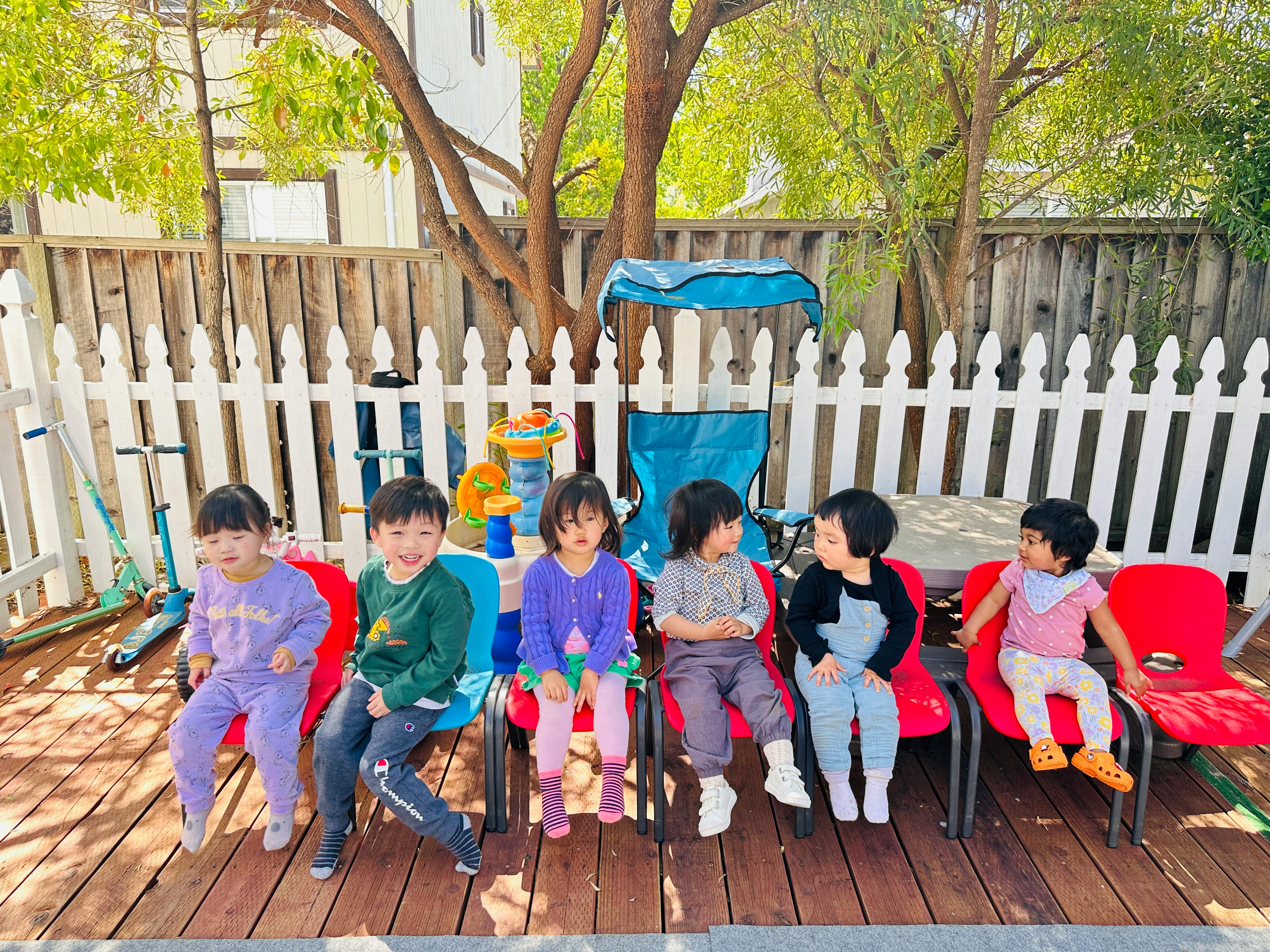 Five children sitting in chairs outdoors