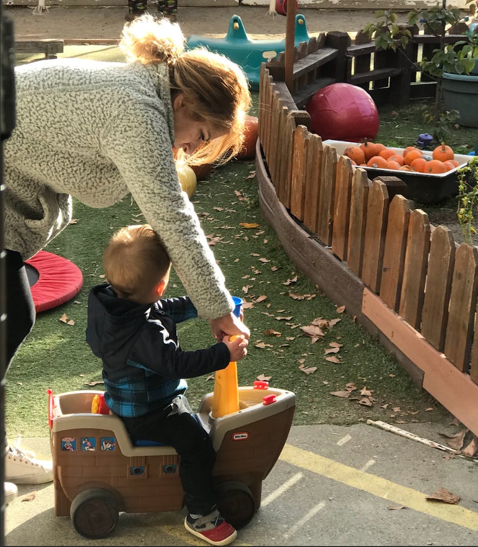 Person helping a child in a toy car