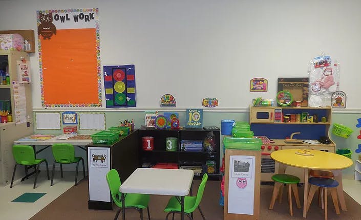 Classroom with small tables and chairs, play kitchen, and wall decorations