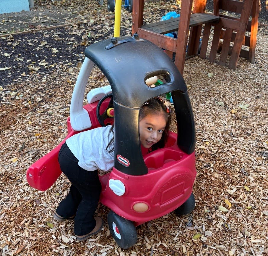 Child looking out from a toy car on a playground