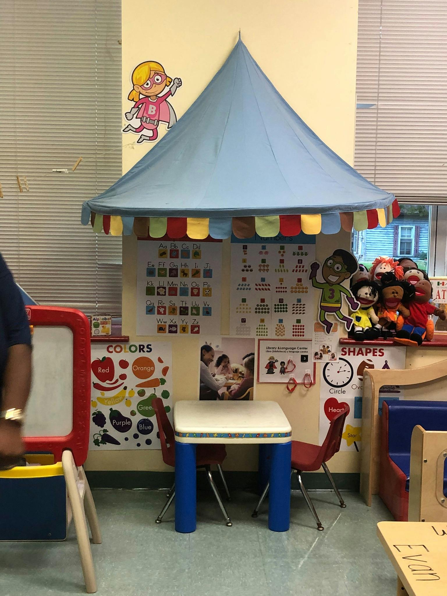 Play area in a classroom with a blue tent, small table, and chairs