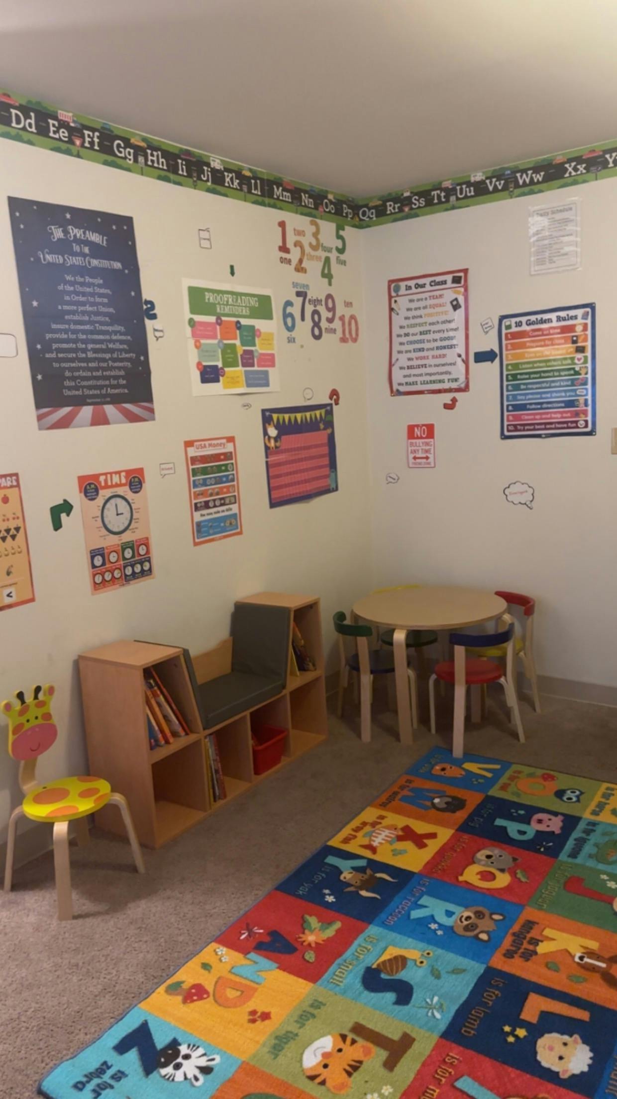 Classroom with colorful rug, small table and chairs, and educational posters on walls