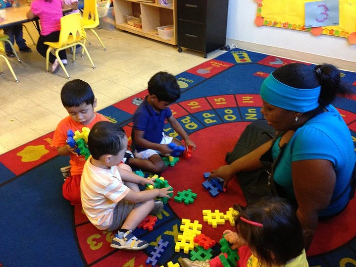 Adult and children playing with building blocks on a rug