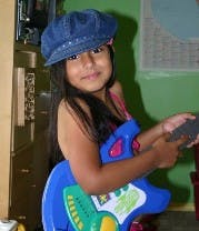 Child wearing a hat and holding a toy guitar