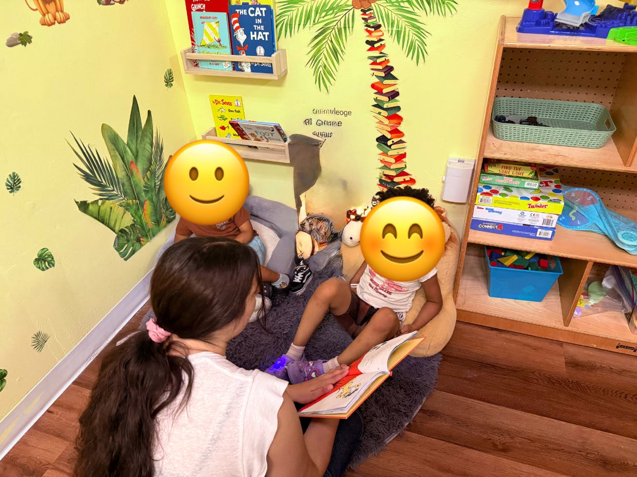 Person reading a book to two children in a classroom