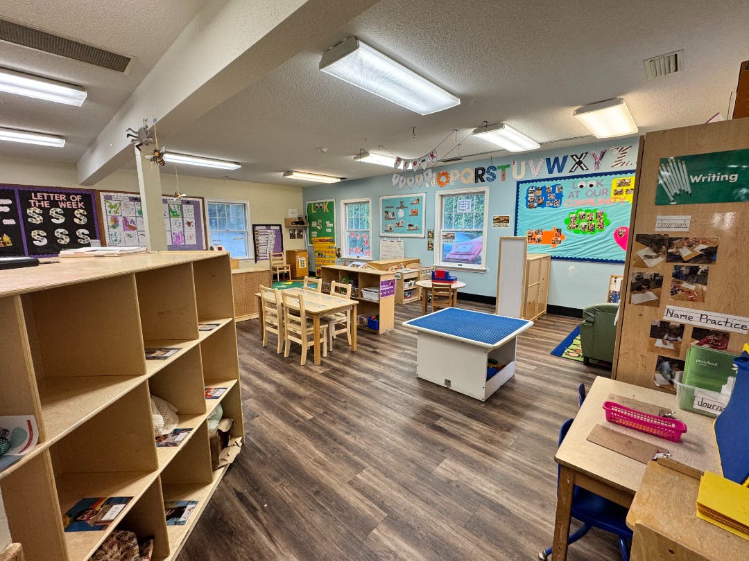 An empty early childhood classroom with tables, chairs, and learning materials