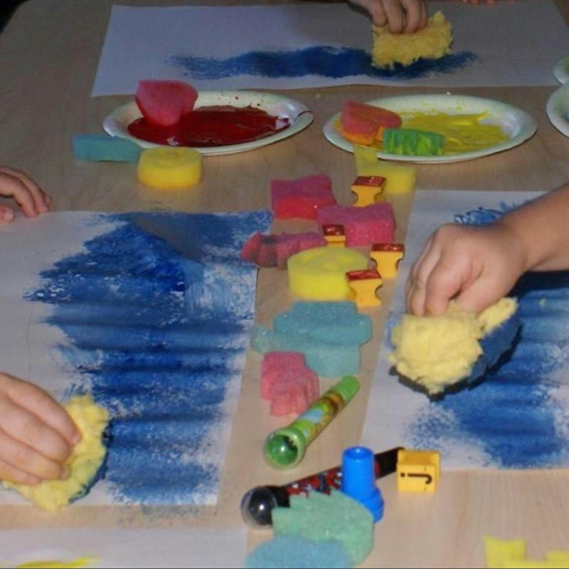 Children sponge painting with blue paint on paper