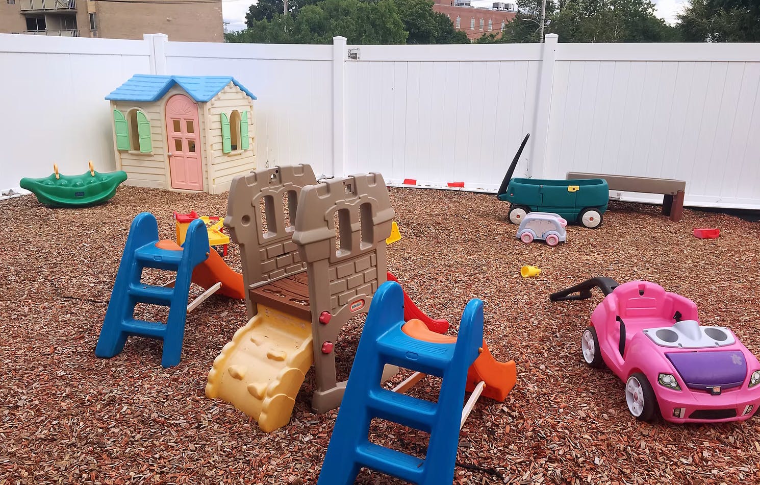 Playground with playhouse, slides, and ride-on toys