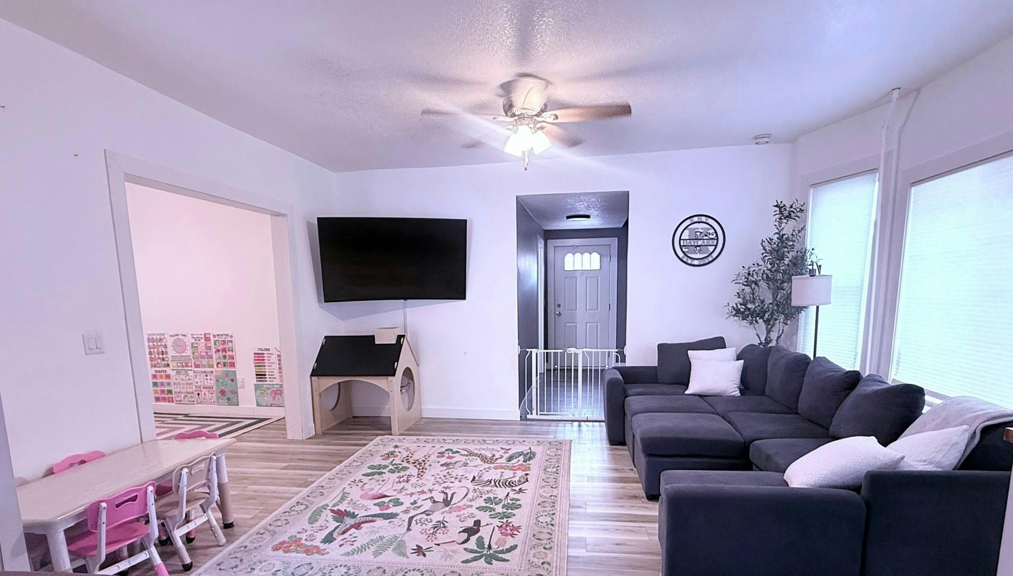 Living room with a sofa, area rug, small table for children, and wall-mounted TV