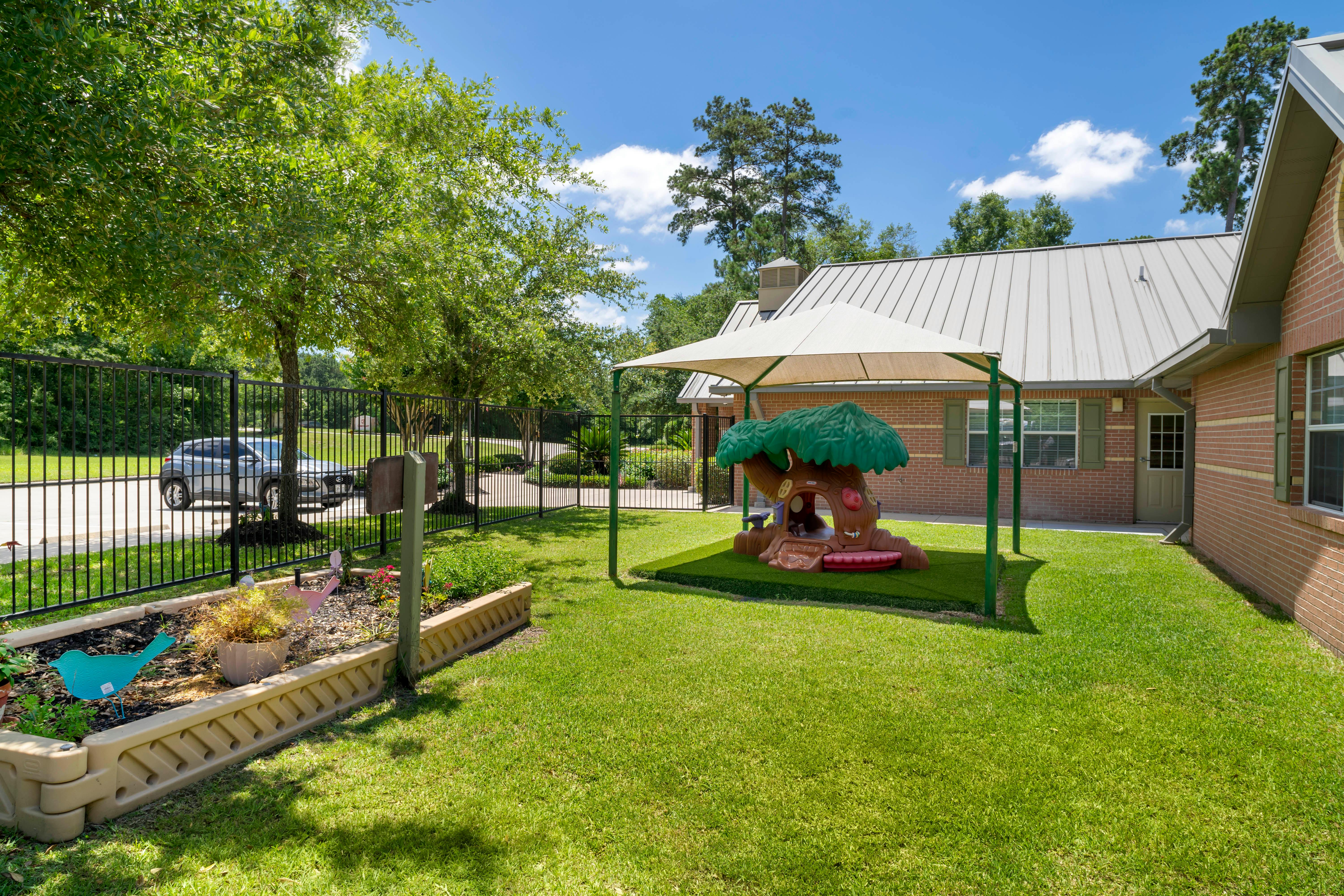 Outdoor play area with a treehouse play structure under a canopy