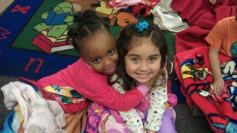 Two children embracing in a classroom
