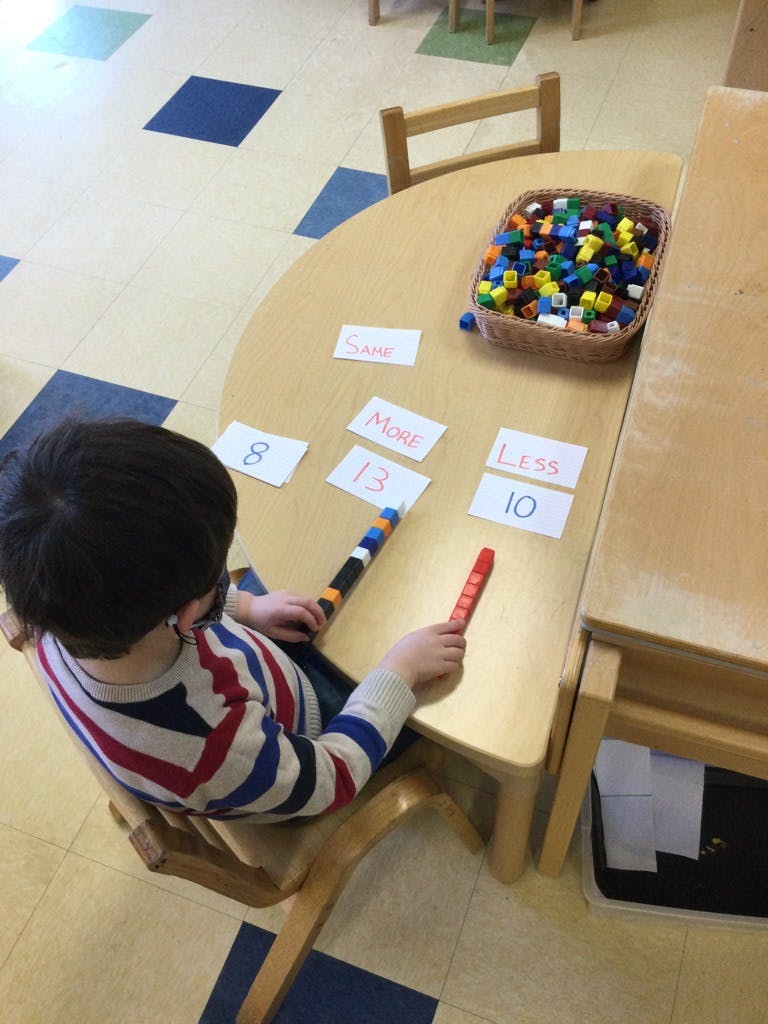 Child at a table with number cards and connecting blocks
