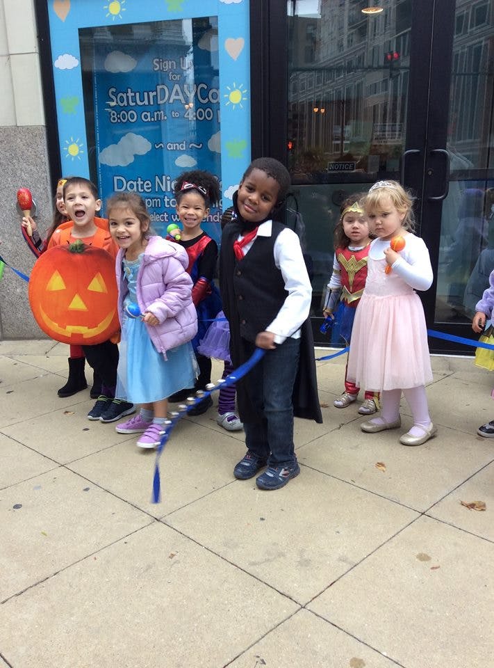 Children in costumes holding a blue ribbon